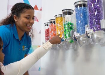 A woman is smiling while looking at the candy in her hand.
